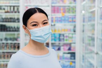 asian customer in medical mask looking at camera in drugstore