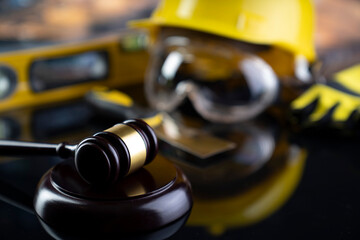 Fototapeta premium Labour law and builiding law concept. Gavel and yellow crash helmet on the shining lawer desk.