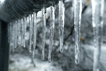 Many small icicles have frozen on a rusty pipe in the street in the winter. High quality photo