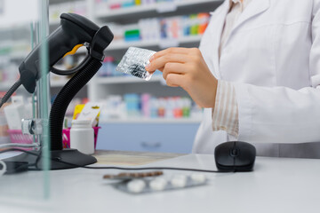 cropped view of pharmacist holding blister pack near scanner in drugstore