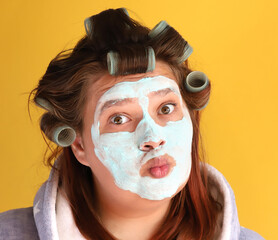 A plus size model gir in curlers and a dressing gown with a cosmetic mask applied to her face