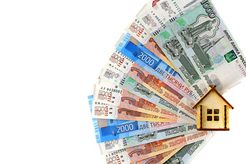 Miniature wooden house on the background of Russian money, fanned out, white background. Real estate object, money background. The concept of buying an apartment, house, real estate. Flat lay.