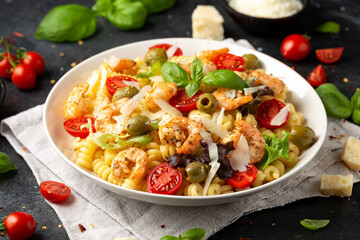 King prawn pasta salad with marinated green olives, cherry tomatoes and parmesan cheese shavings. Healthy food.