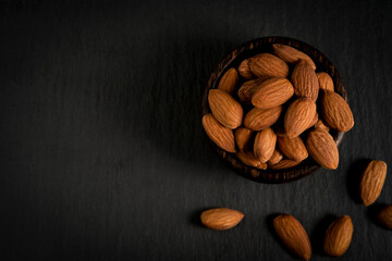 almonds in a dark brown wooden bowl top view