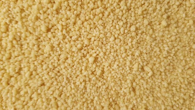 Close up of yellow golden dry couscous top view from above. Macro food us a background with copy space from above. Nutrition vegan vegetarian ingredient concept