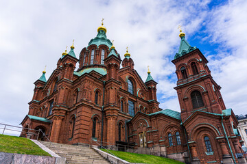 Fototapeta na wymiar Orthodox church made of red stones in Helsinki with a cloudy background