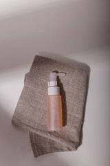 Mock up beige tender pink bottle on sack in solid light with trendy harsh shadows. Care cosmetics container template, no label, no brand