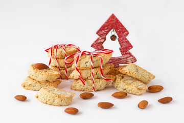 Traditional Italian cookies - cantucci or biscotti with almond and red-white Christmas decorations on white background.