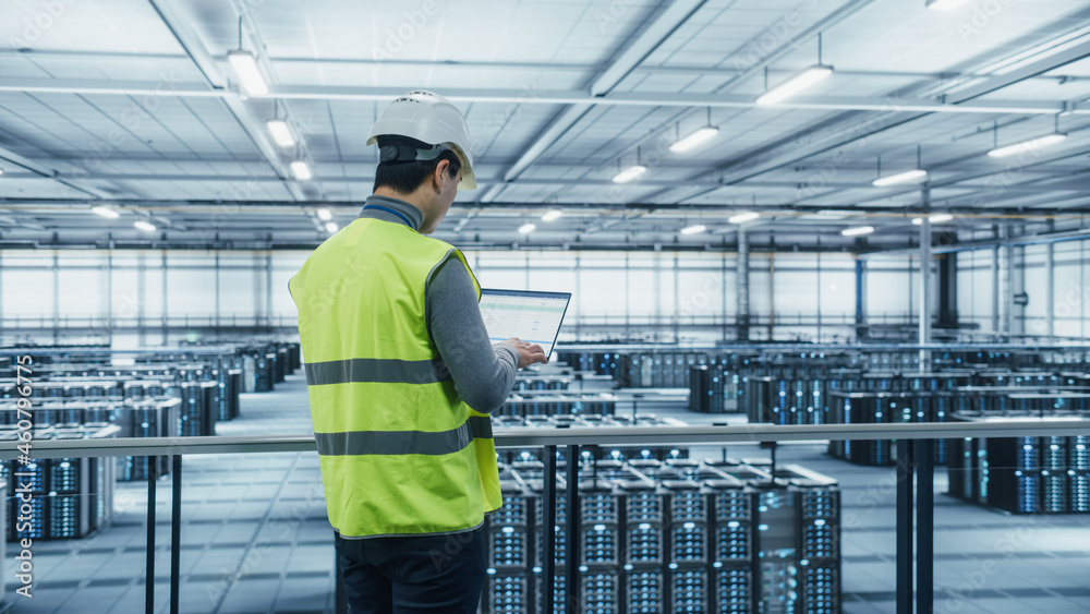 Leinwandbilder Data Center Engineer in High Visibility Vest Using Laptop Computer. Server Farm Cloud Computing Facility with Asian Male System Administrator Working with Data Protection Network for Cyber Security.