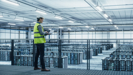 Data Center Engineer in High Visibility Vest Using Laptop Computer. Server Farm Cloud Computing...