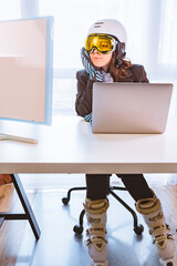 woman in ski equipment working on laptop in office