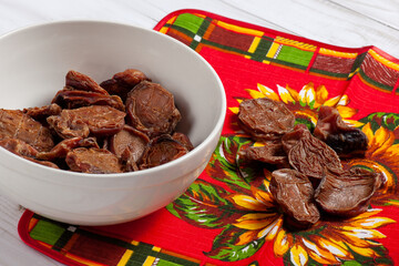 Some dehydrated beef testes for dogs in white bowl and vibrant clothes. Homemade pet treats. Copy...