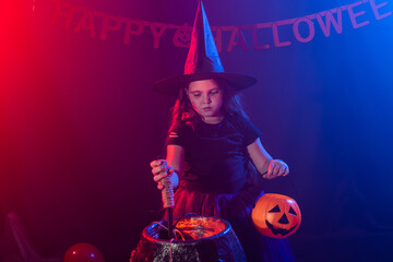 Little witch child cooking potion in the cauldron on Halloween.