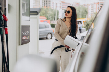 Young woman fueling her car - obrazy, fototapety, plakaty