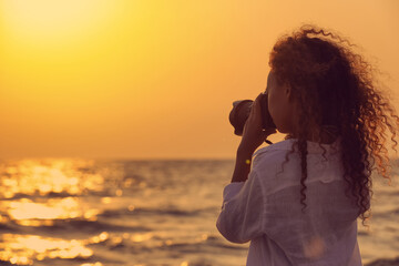 African American photographer taking photo of sea with professional camera at sunset