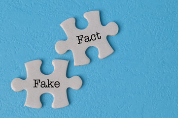 Obraz premium Jigsaw puzzle with text FACT and FAKE isolated on a blue background