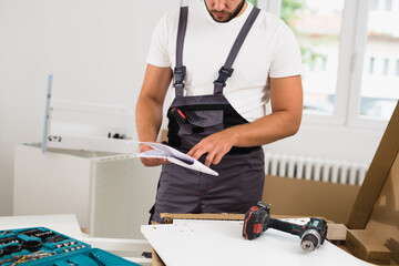 handyman reading user manual while assembling kitchen