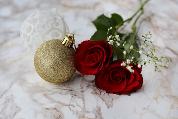 Glitter Christmas baubles and two red roses on a white marble surface. Luxurious and beautiful Christmas theme still life photo with red, white and glitter.