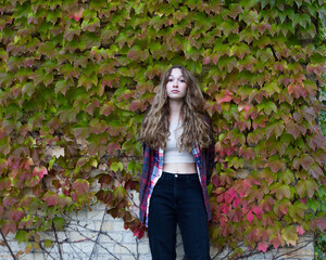 Portrait of gorgeous fair young woman with long curly hair wearing a cropped top and checkered...