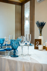 Detail of a wedding dinner setting. banquet table setting with blue napkins and glasses cutlery. vertical photo. table number 2