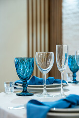 Detail of a wedding dinner setting. banquet table setting with blue napkins and glasses cutlery. vertical photo