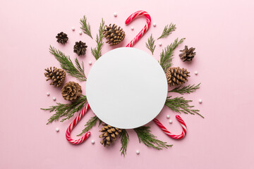 Flat lay Christmas composition. Round Paper blank, pine tree branches, christmas decorations on Colored background. Top view, copy space for text