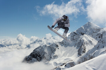 A jumping snowboarder in the mountains. Snowboarding, winter extreme sport.