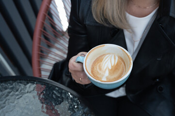 Cropped view of woman drinking coffee in a cafe outdoors