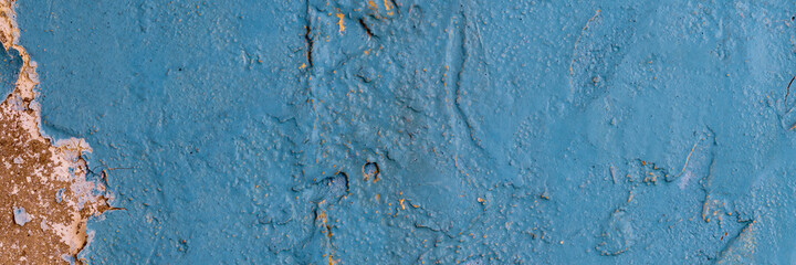 Peeling paint on the wall. Panorama of a concrete wall with old cracked flaking paint. Weathered rough painted surface with patterns of cracks and peeling. Grunge texture for wide panoramic background
