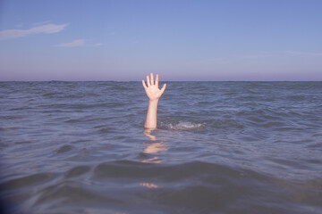 Person submerged on a beach with hand out pretending to be drowning