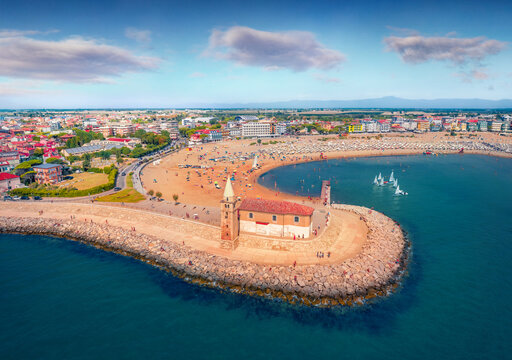 View from flying drone of Madonna dell'Angelo church - small seaside chapel & pilgrimage destination, built in 1751 & dedicated to the Virgin Mary. Aerial summer cityscape of Caorle tow, Italy.