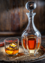 Carafe of whisky and glass of whisky on old wooden cask at the dark background.