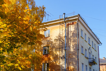 Part of old house in city downtown and autumn maples on sunny day