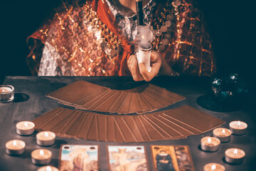Obraz na płótnie Canvas Tarot reader with tarot cards.Tarot cards face down on table near burning candles and crystal ball.