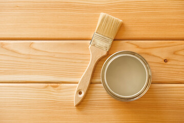 Brush with a jar of paint on a background of natural wooden boards