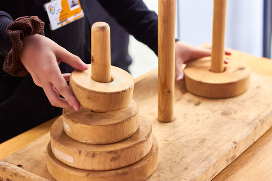 Closeup of white girls hands solving the tower of Hanoi wooden ringstack puzzle game