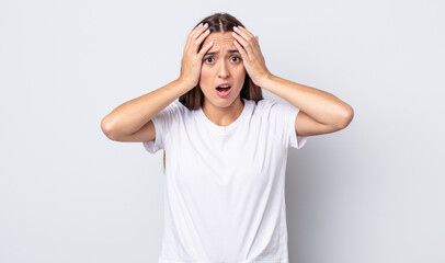 hispanic pretty woman feeling horrified and shocked, raising hands to head and panicking at a...
