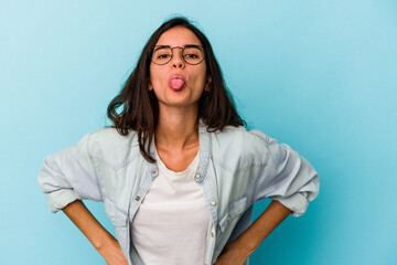 Young caucasian woman isolated on blue background funny and friendly sticking out tongue.