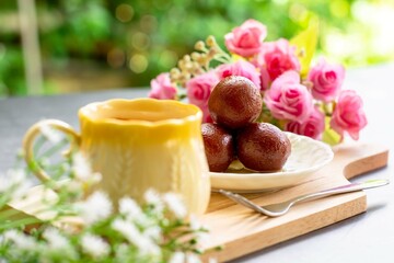 Indian dessert. Gulab jamun traditional sweet dish on a white dish served with hot Indian milk tea.