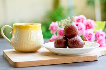 Indian dessert. Gulab jamun traditional sweet dish on a white dish served with hot Indian milk tea.