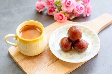 Indian dessert. Gulab jamun traditional sweet dish on a white dish served with hot Indian milk tea.