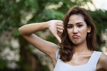 Frowning woman giving rejecting thumb down gesture