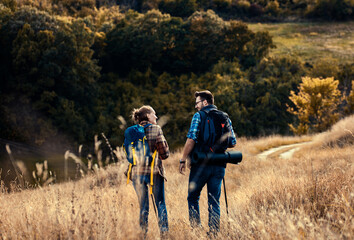 Obraz na płótnie Canvas Couple with backpacks hiking together in nature on autumn day.
