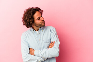 Young caucasian man isolated on pink bakcground dreaming of achieving goals and purposes