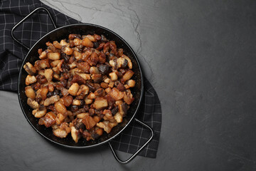 Tasty fried cracklings on black table, top view with space for text. Cooked pork lard