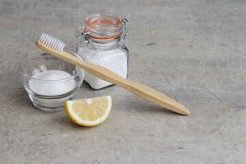Baking soda in a small glass jar, lemon and bamboo toothbrush for tooth whitening at home.  