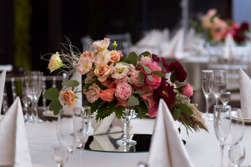 White tablecloths with clear vases and colourful flowers arrangements. Golden colored plates, peavh napkins, table numbers and mirror centerpieces.