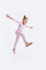 Bottom view. Portrait of little active Caucasian preschool girl stepping isolated over white background