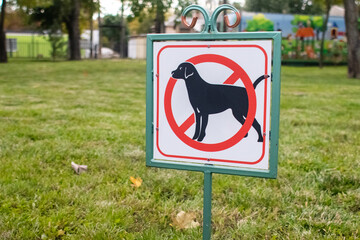 Close-up of no dog sign. Street pointer on a background of green grass. Ban on defecation and running of pets on park lawns and green spaces. Without people. No dogs allowed. Place for text