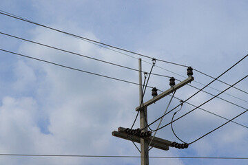 Electric poles with high voltage cables cross over pass isolated on blue sky and white cloud background closeup.